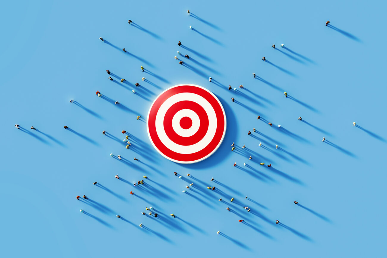Human crowd gathering around a red bulls eye on blue background. Horizontal composition with copy space. Clipping path is included. Marketing and target audience concept